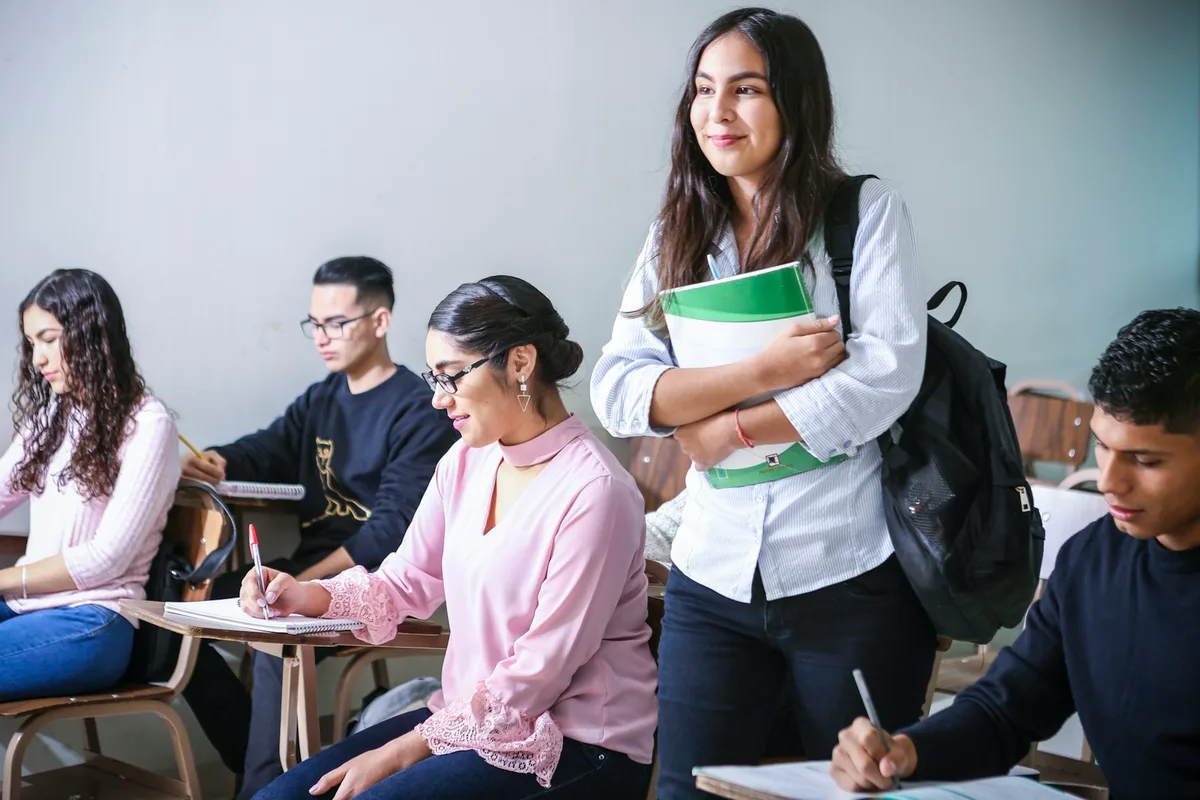 Young adult students writing at desks during a class