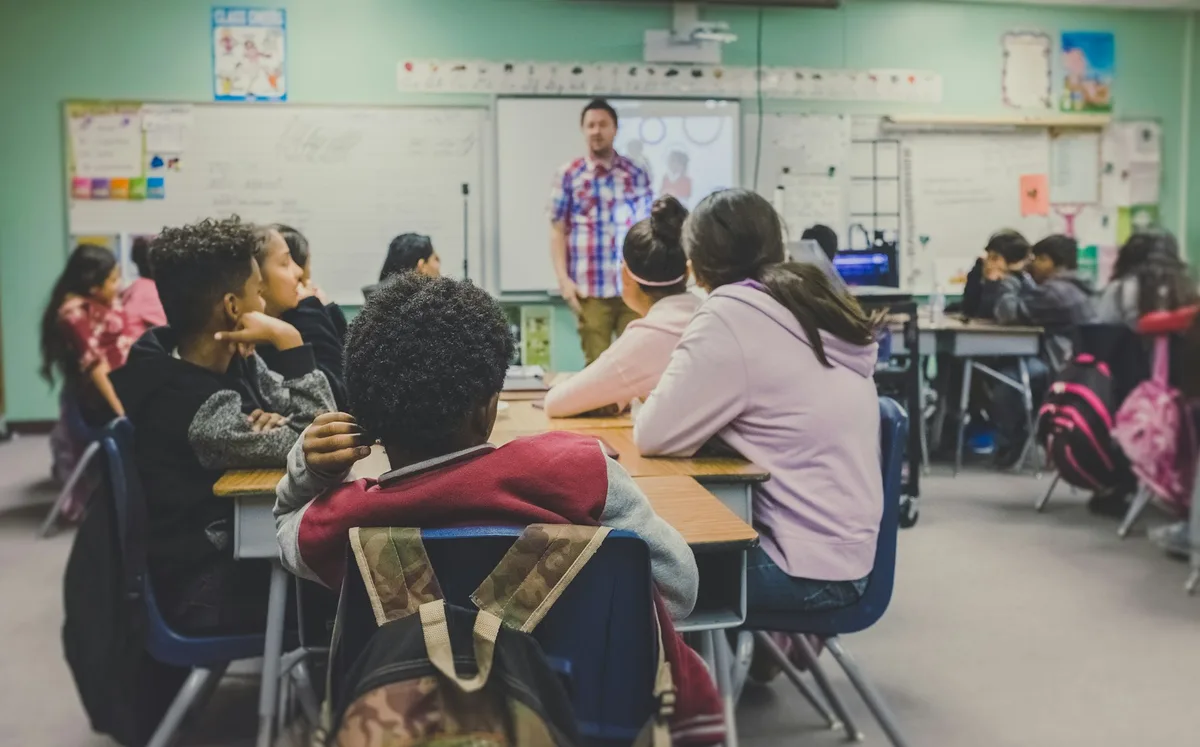 Teacher at the front of a school classroom with students at their desks