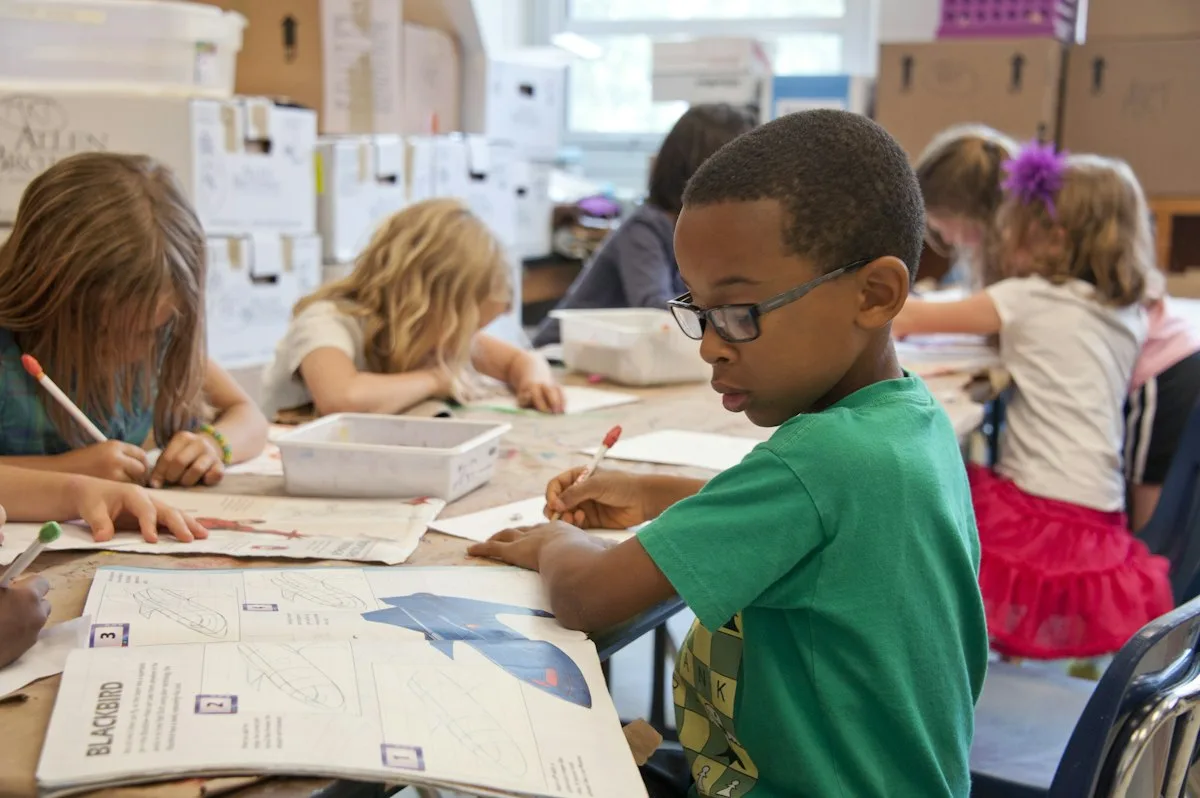 Primary students drawing and writing at their classroom desks