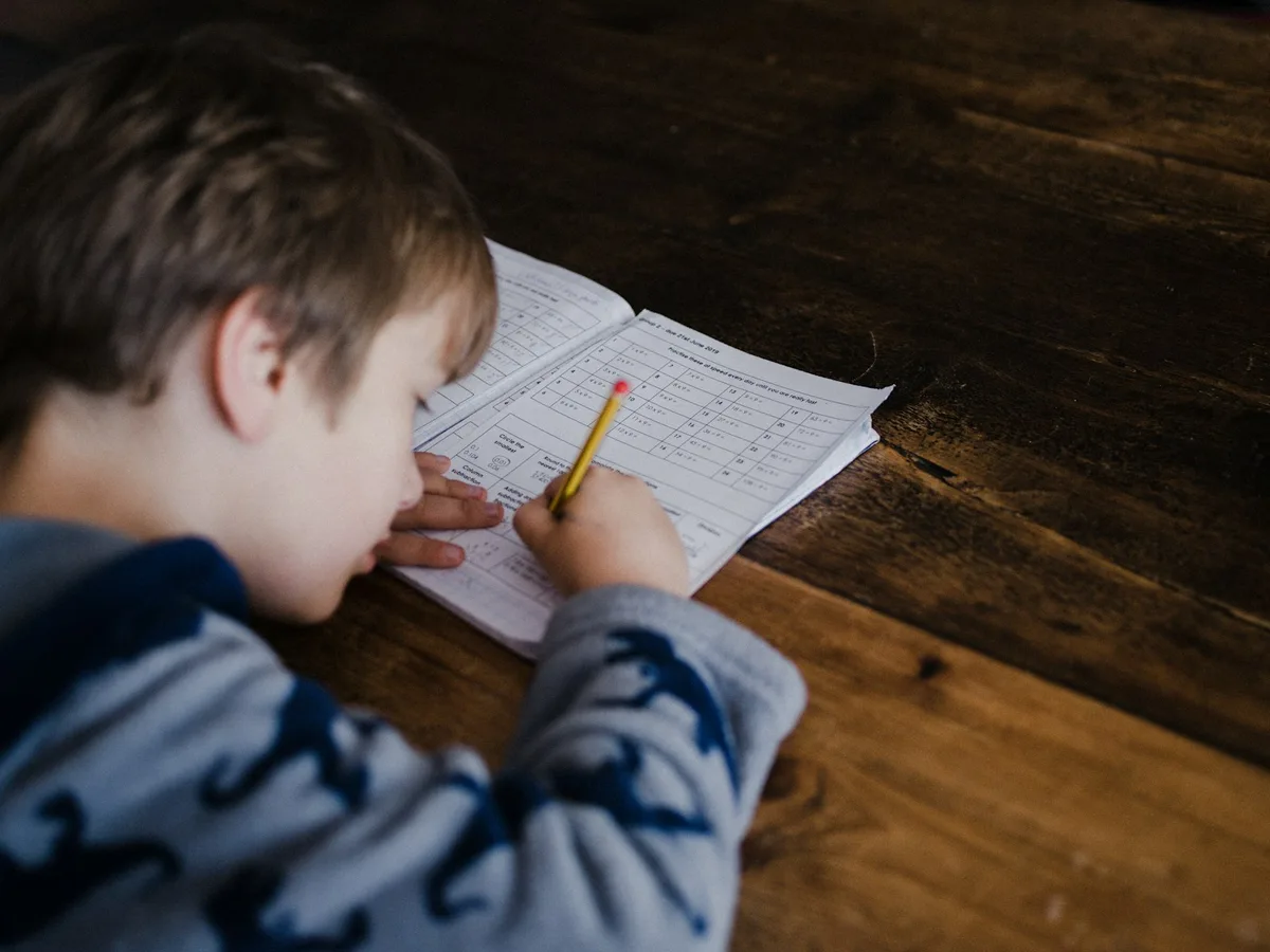 Primary student working through a maths worksheet with a pencil